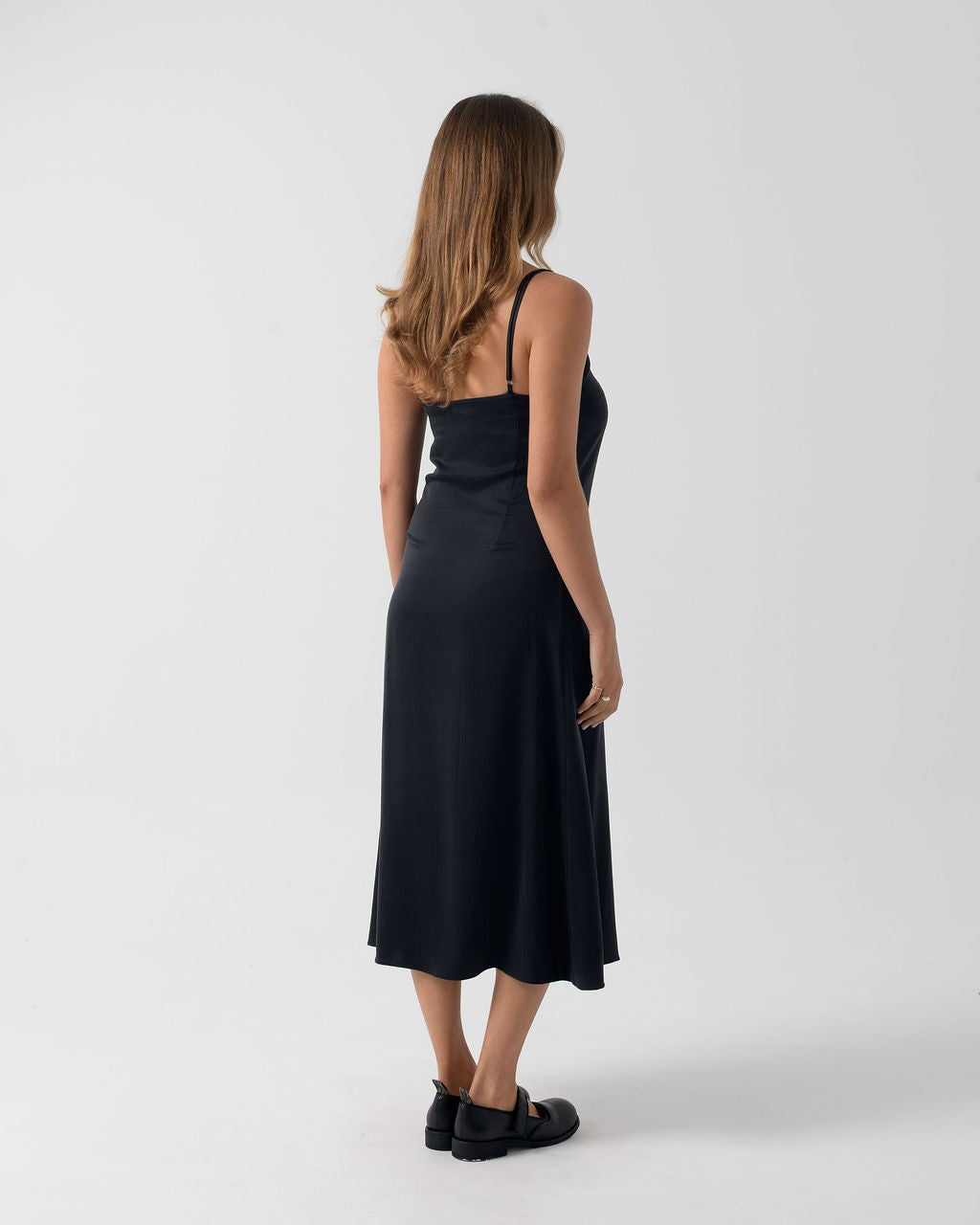 Three-quarter back view of the Washed Black Bias Slip Dress with adjustable straps and a fluid silhouette.