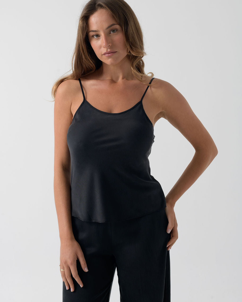 Portrait view of the Washed Black Camisole in stonewashed silk with thin adjustable straps and a relaxed drap