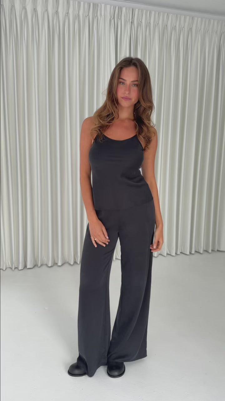 Model wearing the Washed Black Camisole in stonewashed stretch silk with a relaxed drape, thin adjustable straps and a classic 90s-inspired silhouette.
