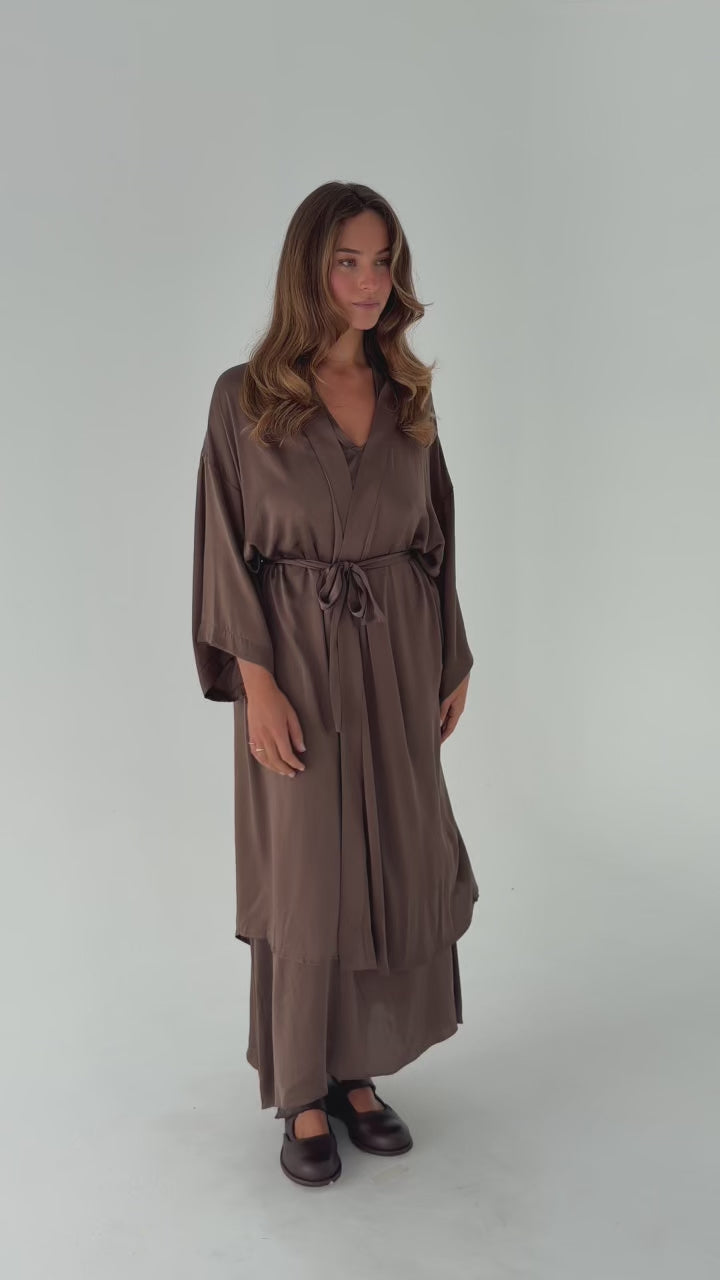 Model wearing the Moka Stretched Silk Robe in stonewashed stretch silk, showcasing the relaxed silhouette, side pockets, adjustable back waist tie and fluid movement over the matching silk dress.