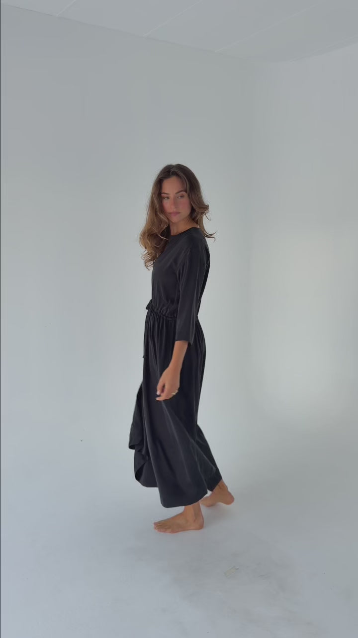 Model wearing the Washed Black Drawstring Dress in stonewashed stretch silk with a relaxed full-length silhouette, adjustable drawstring waist and fluid drape.